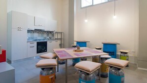 A modern kitchen with white cabinets, a gas stove, and a blue accent wall. There is a table with papers and a small wooden box. - Hostelleria (Trapani)
