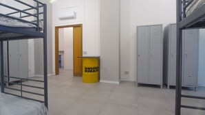 A dormitory room with bunk beds, a wooden door, and lockers. - Hostelleria (Trapani)