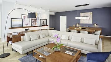 Ein modernes Wohnzimmer mit einer Eckcouch, einem Glastisch und einem Essbereich mit Holztisch und Stühlen.