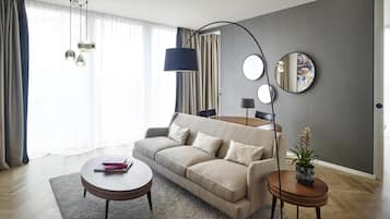 Uma sala de estar moderna com sofá, mesa de centro e mesa lateral, um espelho e um vaso com planta.
