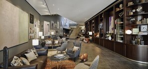 A modern living room with a sofa, armchairs, a coffee table, and a bookshelf.