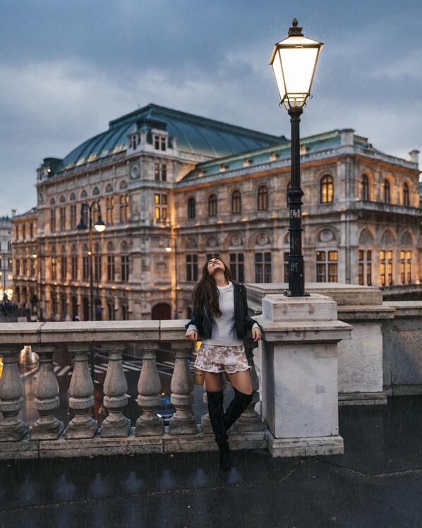 A person leaning on a stone balustrade with a historic building in the background.