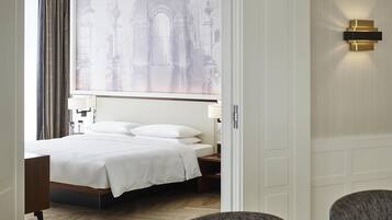 Une chambre d’hôtel comprenant un lit, une table de chevet, une lampe, une chaise et donnant sur un bâtiment remarquable.