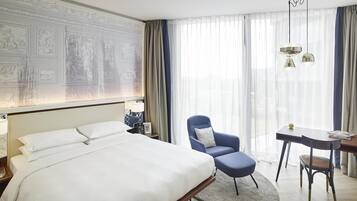 Una habitación de hotel con una cama grande, un escritorio, una silla y una ventana con cortinas.