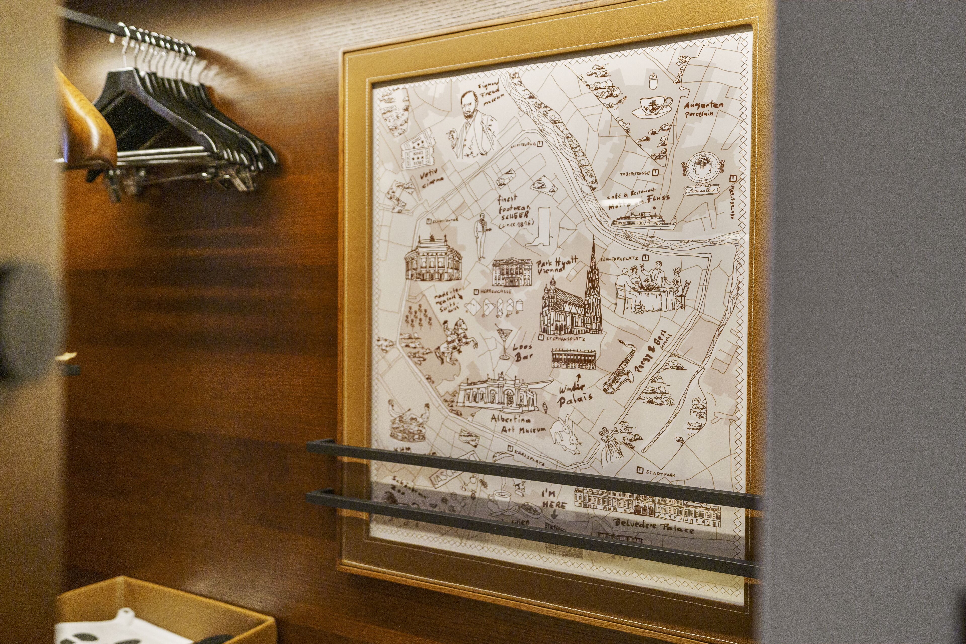 Un mapa enmarcado de una ciudad con puntos de referencia y una pared de madera con perchero.