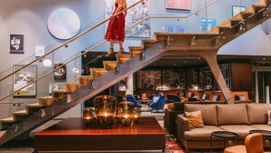 Un hall d’hôtel moderne avec un escalier, un espace salon et des œuvres d’art accrochées aux murs.