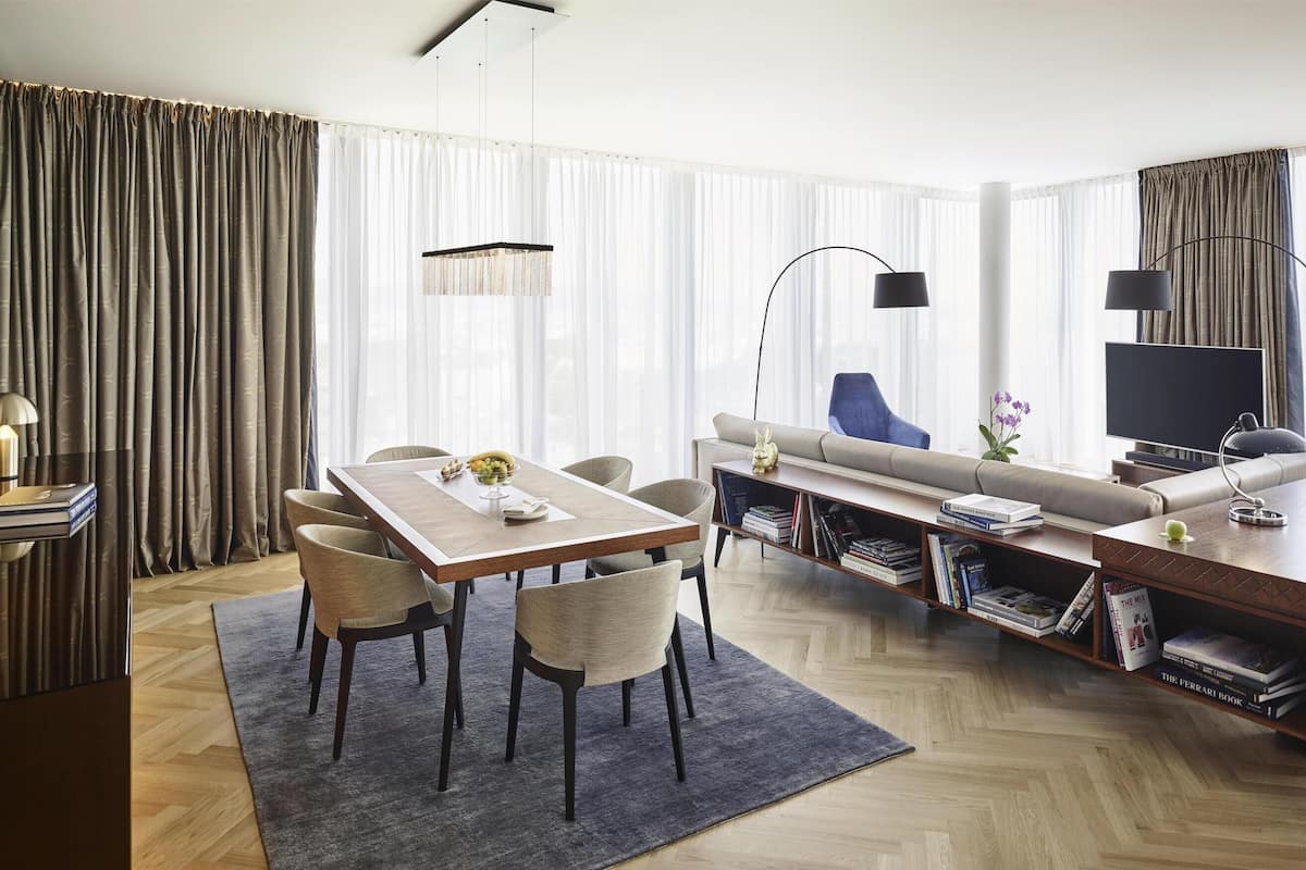 Habitación de hotel moderna con comedor, sofá, televisor y estanterías.