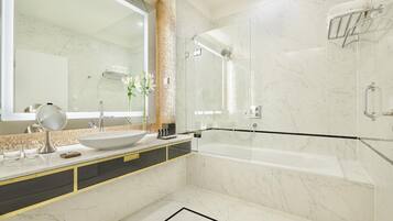 Un baño moderno con un espejo grande, un lavamanos blanco, una bañera y una zona de ducha con mampara de vidrio.