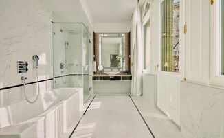 A modern bathroom with a glass-enclosed shower, a large bathtub, and a vanity with a mirror.