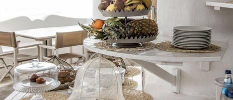 Una mesa de buffet con una presentación de frutas en tres niveles, pan y diversos platos.