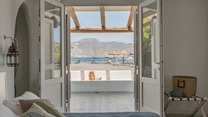 Ein Schlafzimmer mit offener Bauweise und Blick auf Strand und Boote.