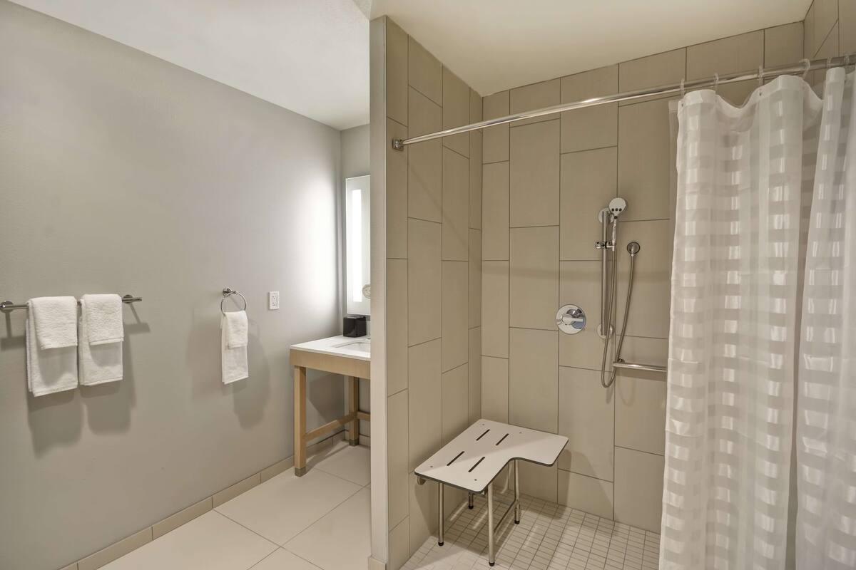 Ein modernes Badezimmer mit Dusche, einem kleinen Tisch und einem Handtuchhalter.