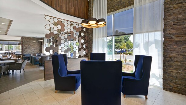 A modern hotel lobby with a seating area, large windows, and a decorative wall. - Hyatt Place Fresno (Fresno)