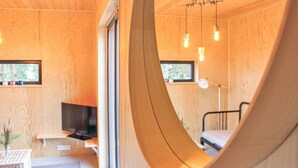 A modern interior with wooden walls, a curved wooden structure, a bed, a desk, a television, and hanging lights. - Beautiful home in Nowe Warpno with WiFi (Nowe Warpno)
