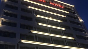 Un edificio de varios pisos con letreros iluminados que dicen "SIMISSA HOTEL".