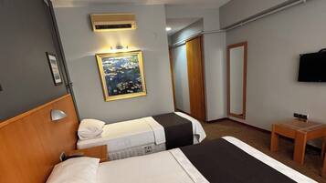 A hotel room with two beds, a desk, a TV, a painting, and a wardrobe.