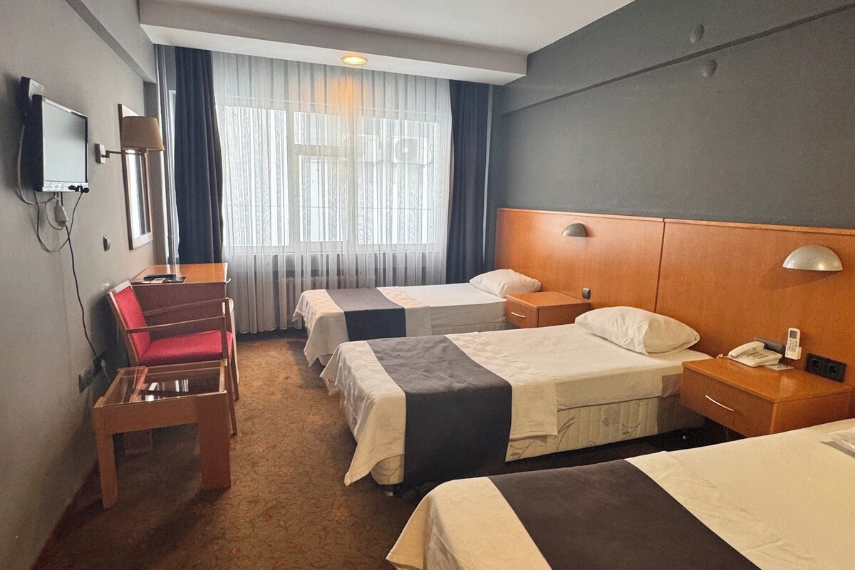 Una habitación de hotel con dos camas, un escritorio, una silla y un televisor.