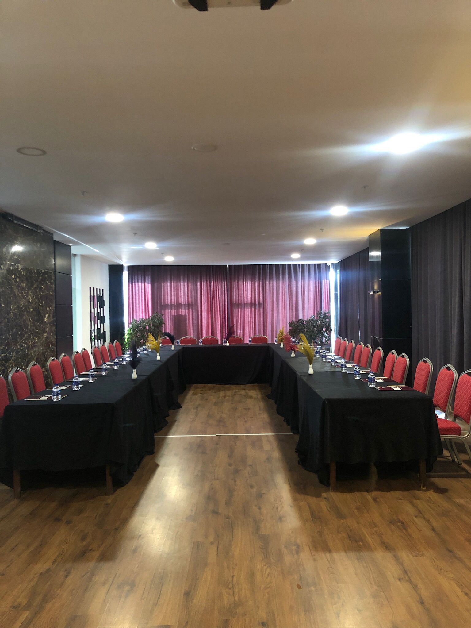 A conference room with a long table, red chairs, and a black tablecloth.