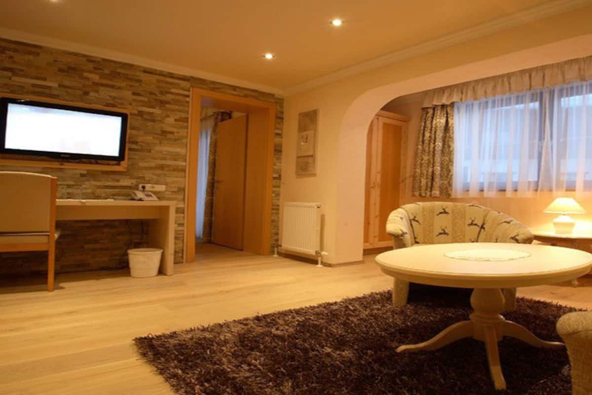 A living room with a television, a round coffee table, a sofa, and a lamp.