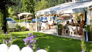 An outdoor café with tables and chairs, surrounded by a white picket fence and greenery. - Cafe-Pension Erika (Eben am Achensee)