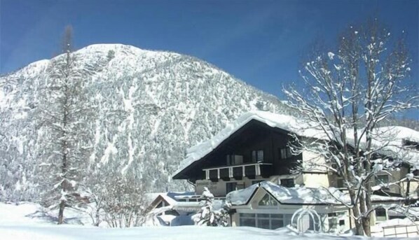 A snow-covered mountain with a lodge featuring a large wooden structure, surrounded by snow-covered trees and buildings.