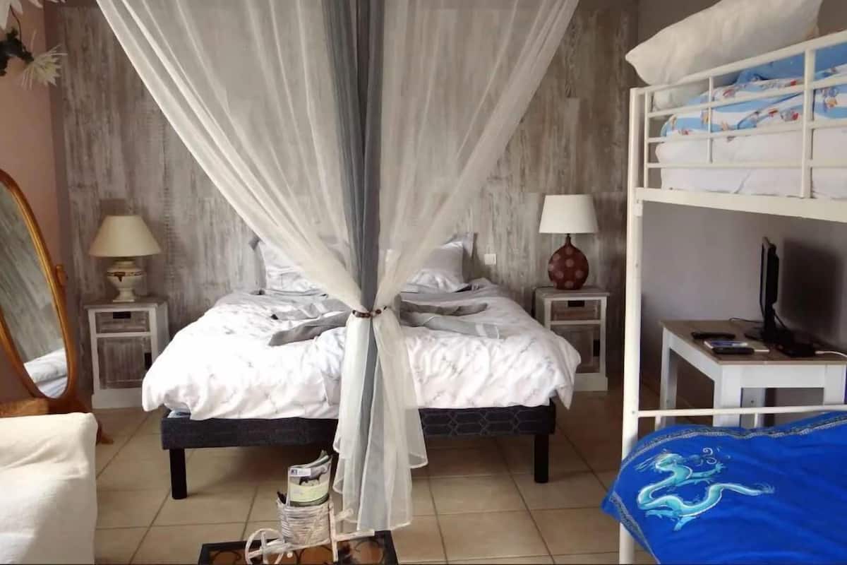 A bedroom with a bed, a nightstand, a lamp, a television, and a bunk bed.
