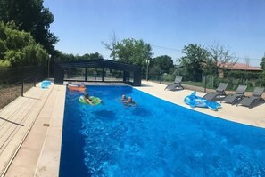 Una piscina al aire libre, sombrillas, sillones reclinables de piscina