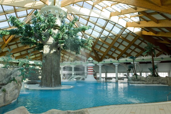 An indoor swimming pool with a large tree, rocky formations, and a lighthouse structure. - Happy Camp Mobile Homes in Camping Terme Catez (Brezice)