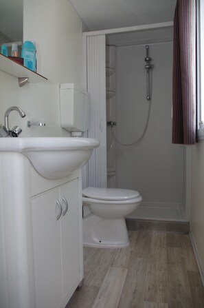 A bathroom with a white sink, toilet, and shower. - Happy Camp Mobile Homes in Camping Terme Catez (Brezice)
