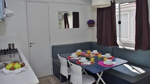 A compact kitchen with a gas stove, a sink, and a dining area with a table set for breakfast.