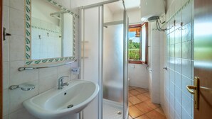 A bathroom with a sink, mirror, and shower.