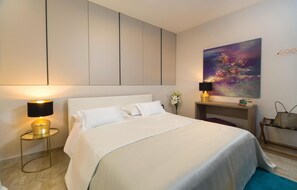 A modern hotel room with a large bed, bedside lamps, a painting on the wall, and a small table with books and a handbag. - Stunning home in Loviste (Loviste)