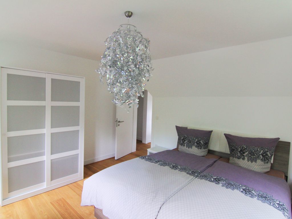 A bedroom with a large bed, a chandelier, and a wardrobe.