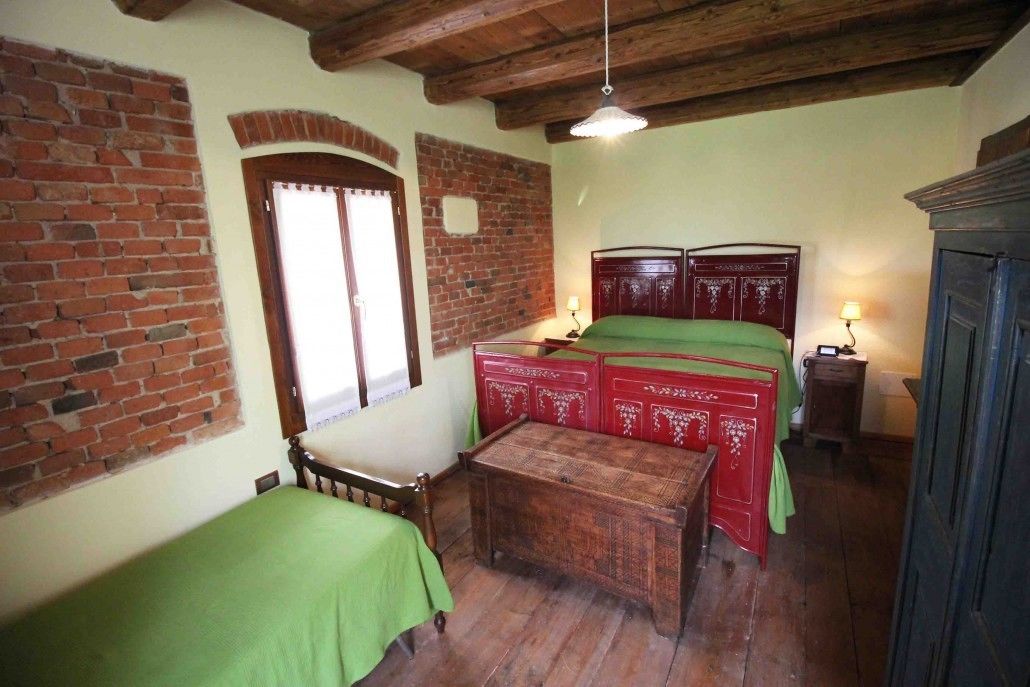 A room with a bed, a wooden table, a brick wall, and a window.