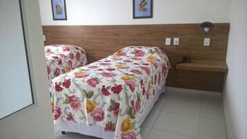 Ein Zimmer mit zwei Betten, jeweils mit floralem Bettbezug, einem Holzkopfende und einem Nachttisch mit Lampe.