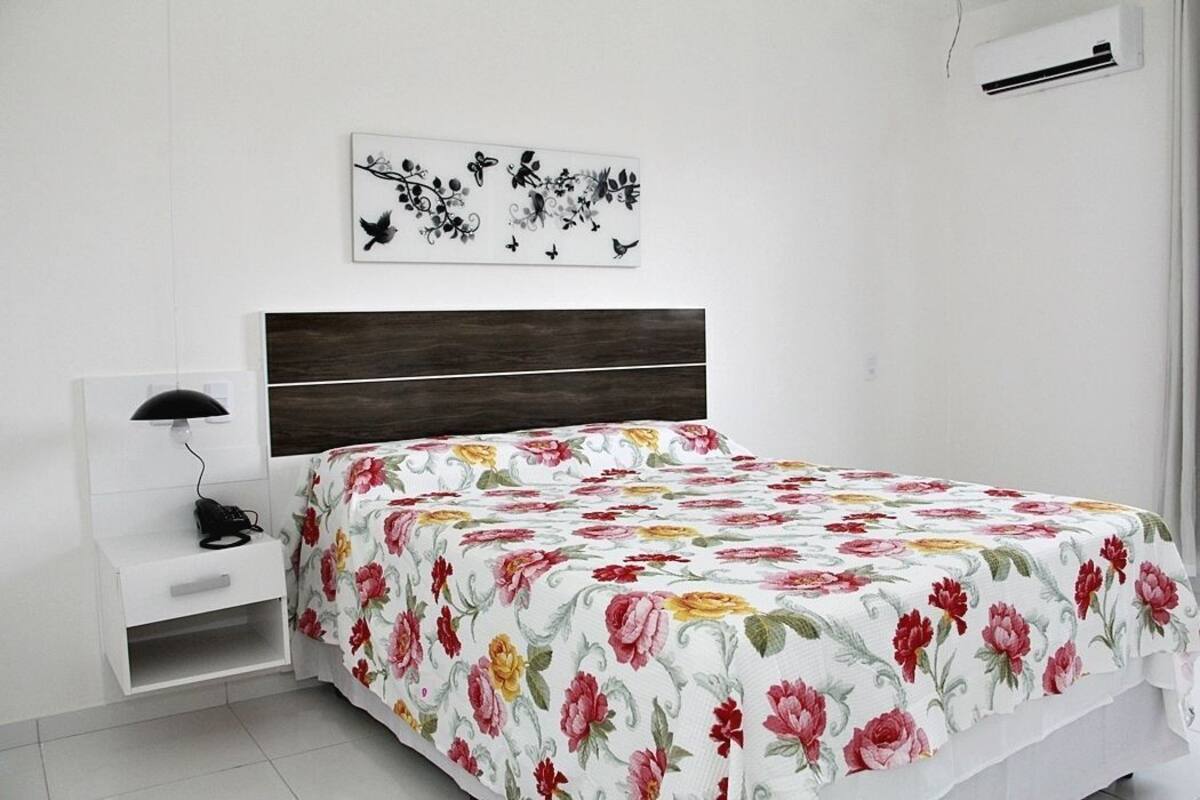 A bedroom with a bed, bedside table, lamp, and wall art.