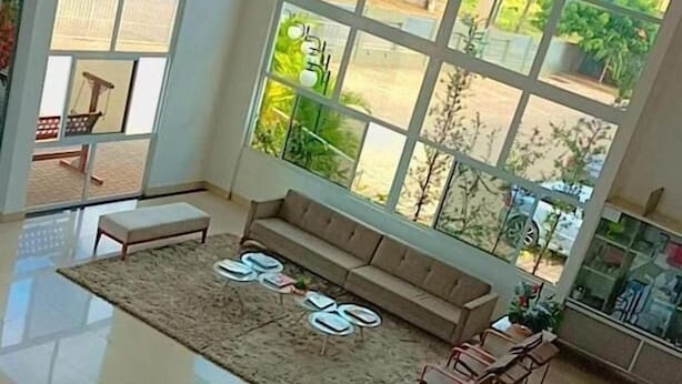 A spacious living room with a large window offering a view of a garden and a distant cityscape. - France Hotel (Guarabira)