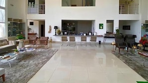 A spacious living area with a high ceiling, a fireplace, and a seating arrangement. - France Hotel (Guarabira)