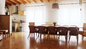 A spacious dining area with a wooden ceiling and a large table surrounded by wicker chairs. - Haus EMG Hockenheim (Hockenheim)
