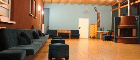 A spacious room with a wooden floor, a sofa set, a bench, and a fireplace.