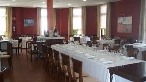 Zona pranzo con diversi tavoli apparecchiati, sedie e un'ampia finestra che fa entrare luce naturale.