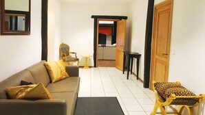 A living room with a sofa, a small table, and a leopard-print ottoman. There is a door leading to a kitchen area. - Ferienhaus Villa EMG Düsseldorf Krefeld (Krefeld)