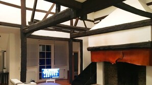A modern living room with exposed wooden beams, a fireplace, and a comfortable seating area. - Ferienhaus Villa EMG Düsseldorf Krefeld (Krefeld)
