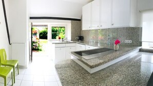 A modern kitchen with white cabinets, a granite countertop, and a window providing natural light. - Ferienhaus Villa EMG Düsseldorf Krefeld (Krefeld)