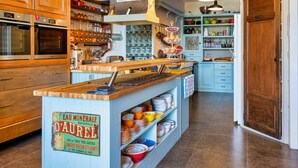 A kitchen with wooden cabinets, a central island with a sign, and various kitchen utensils. - Villa Limonade (Olonzac)