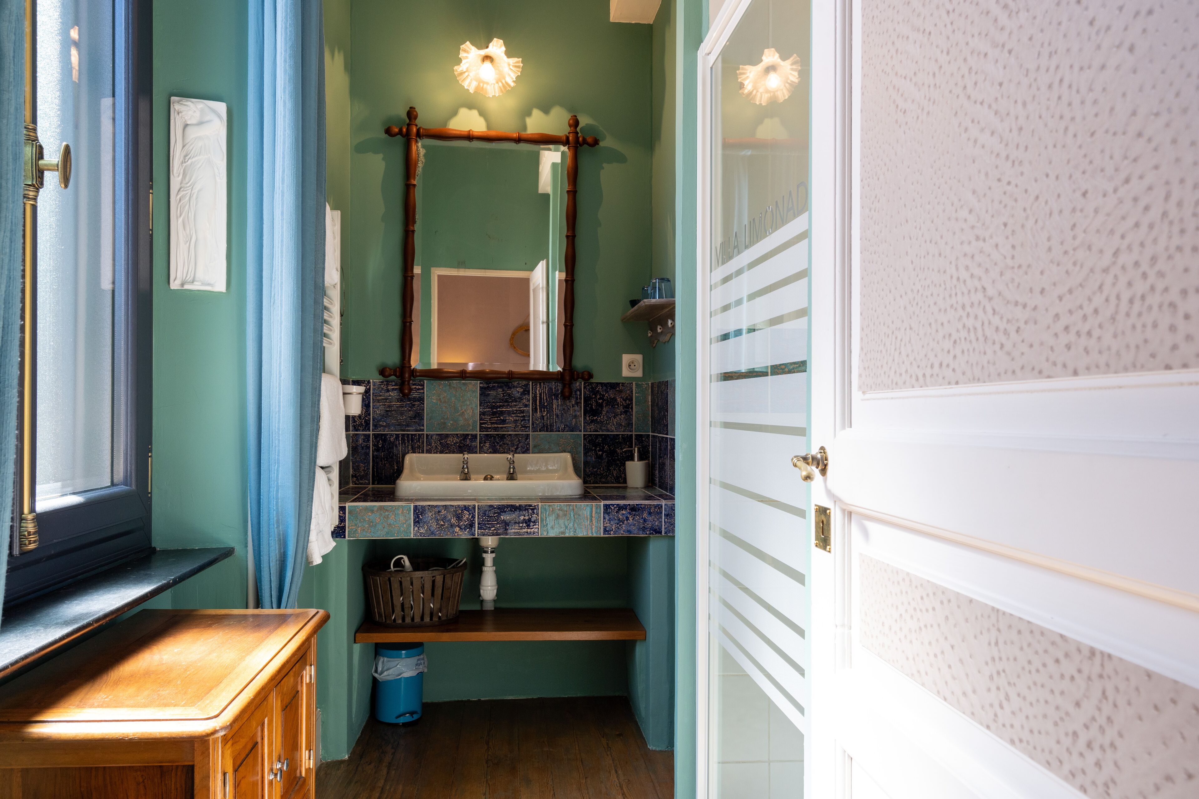 A bathroom with a sink, mirror, and a window with curtains.
