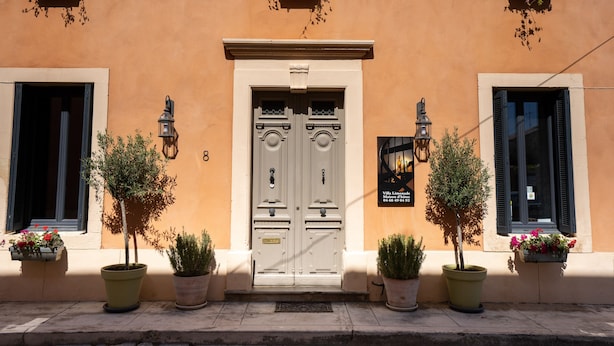 A building with a double door entrance, potted plants, and flower boxes on the windowsills. - Villa Limonade (Olonzac)