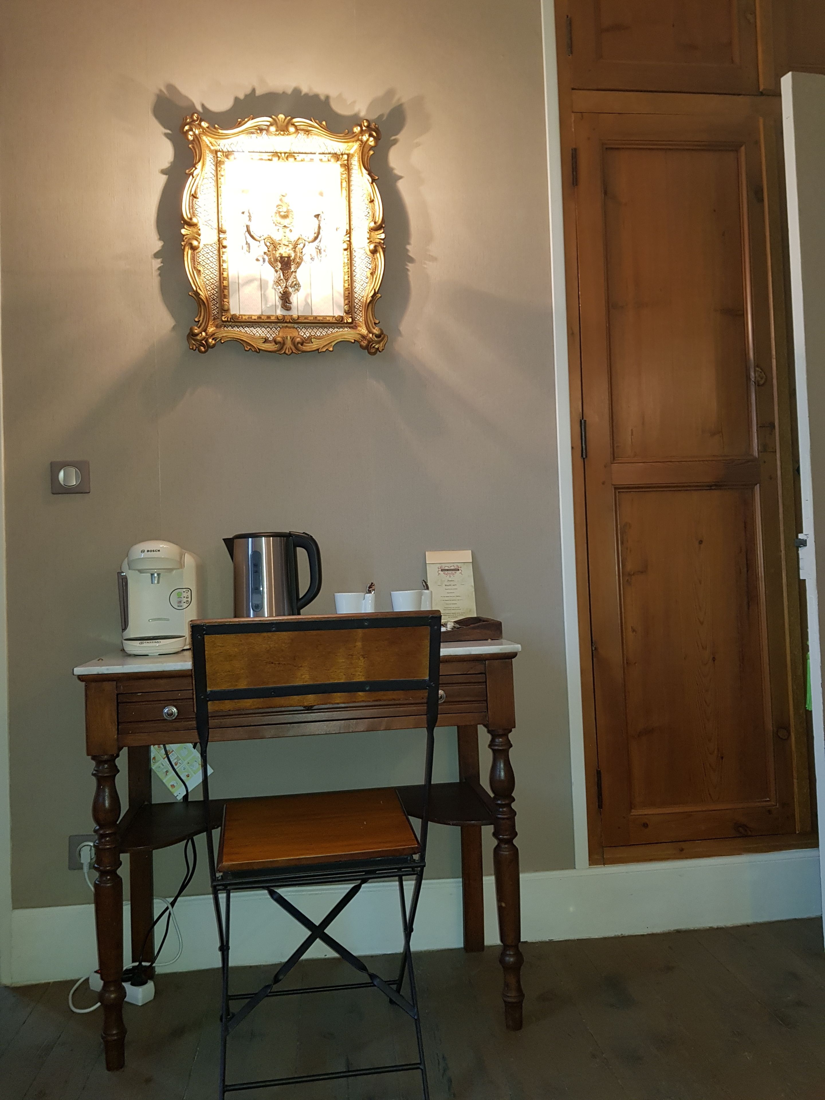 Een houten bureau met een koffiezetapparaat, een waterkoker en een ingelijste foto aan de muur.