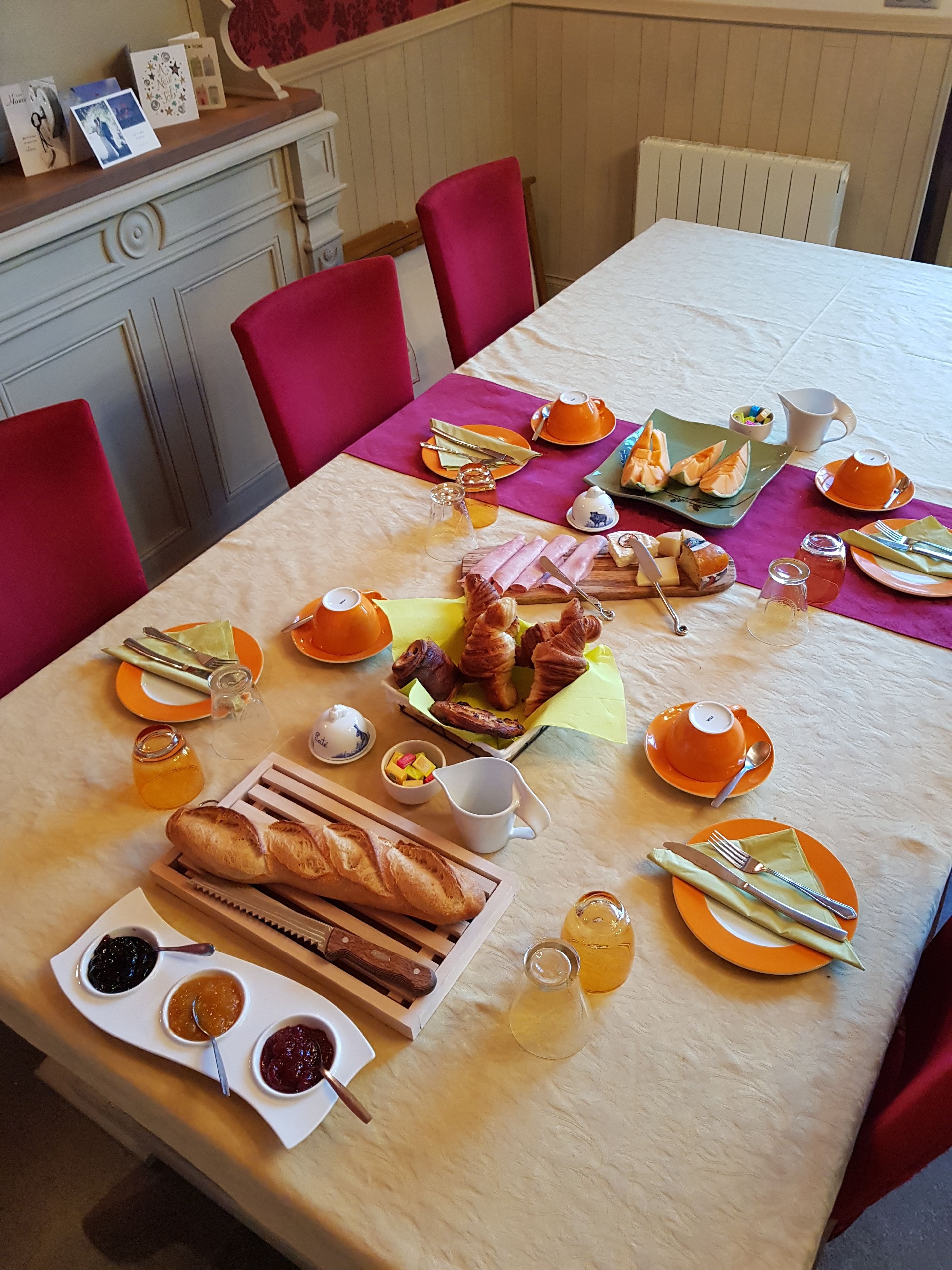 Een ontbijttafel gedekt met croissants, brood, jam en gebak.