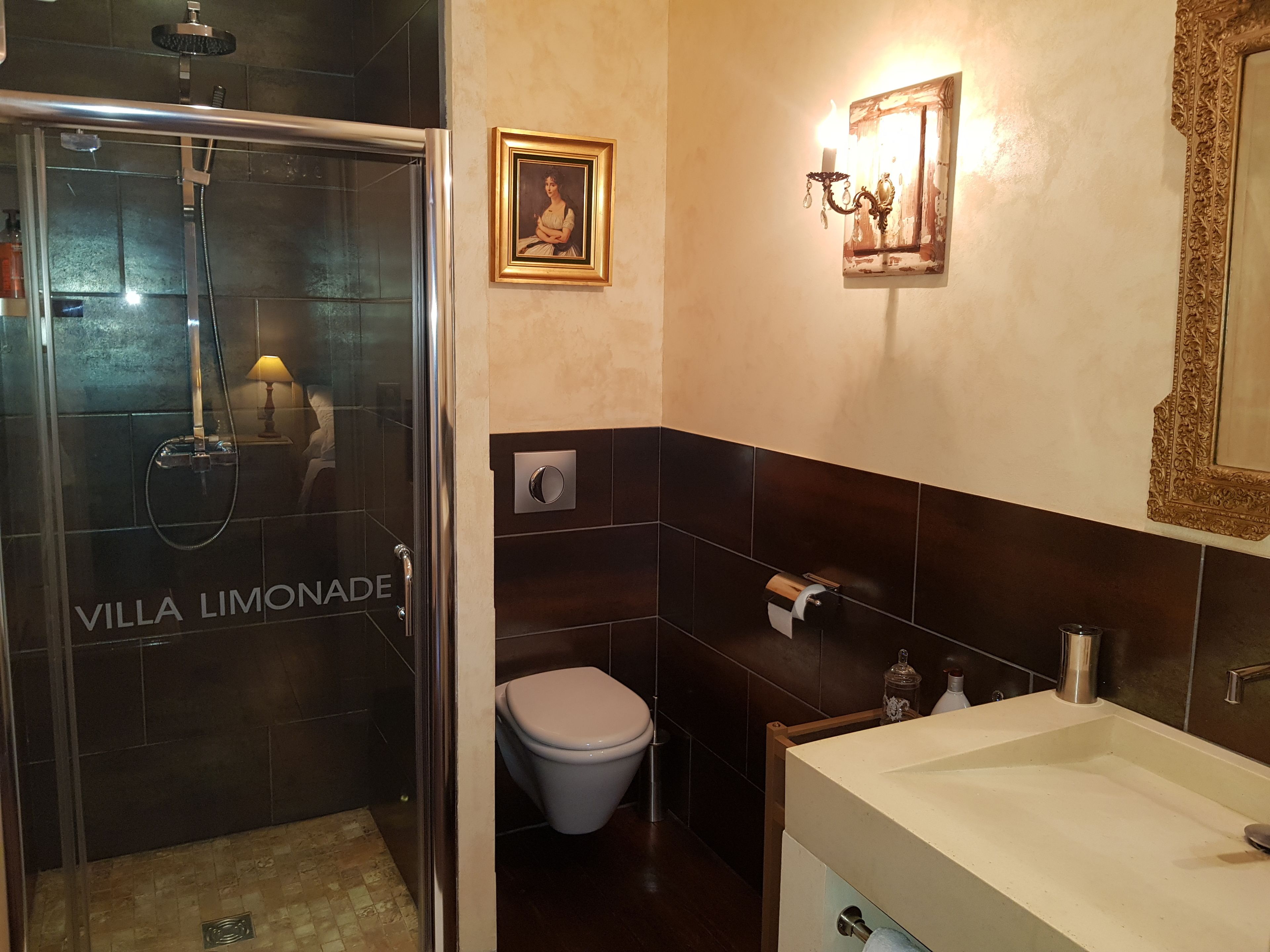 A bathroom with a glass-enclosed shower, a toilet, and a sink.